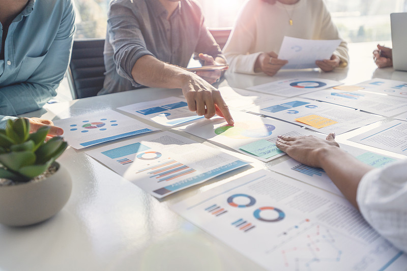 在商业演示或研讨会上,在董事会会议室的桌子上处理文书工作的多种族群体。图片下载