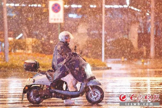 1月21日23时许,长沙城区上空开始飘洒雪花。图为夜幕下顶风冒雪晚归的市民。长沙晚报全媒体记者 王志伟 摄