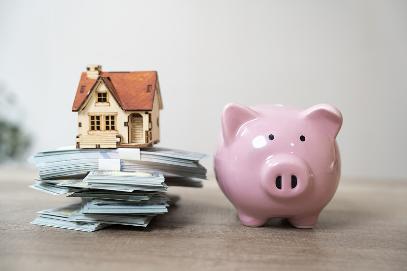 小猪储蓄罐放在一堆钱上面图片下载