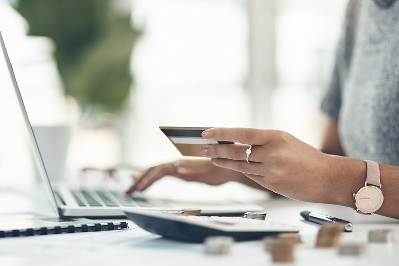 近距离拍摄了一个陌生的女商人在办公室使用笔记本电脑和信用卡图片下载