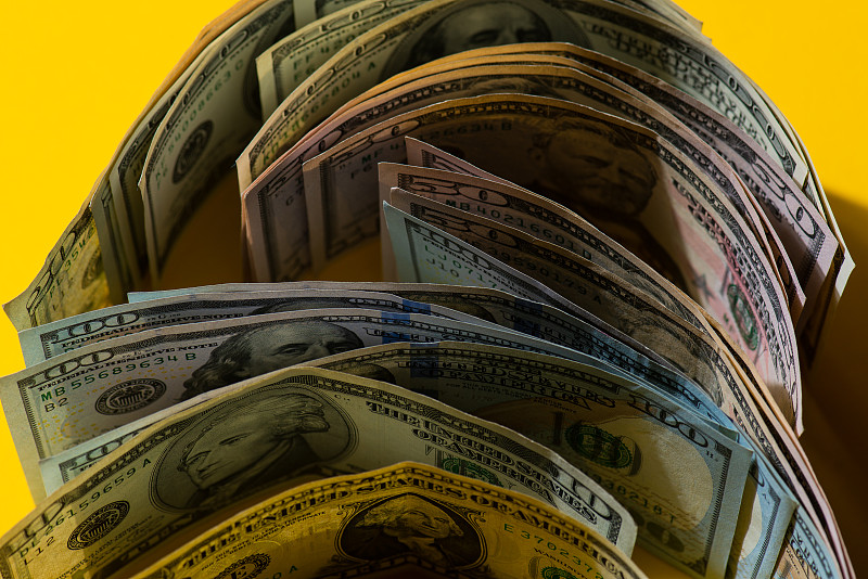 黄色背景上的一卷100美元美钞,特写图片下载