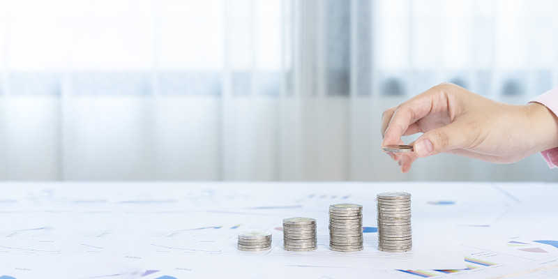 手里拿着一堆钱硬币,以显示业务增长的概念。图片下载