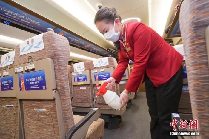 资料图：2月28日晚，在威海开往北京南的G470次列车上，乘务员对座椅扶手消毒。/p中新社记者 贾天勇 摄