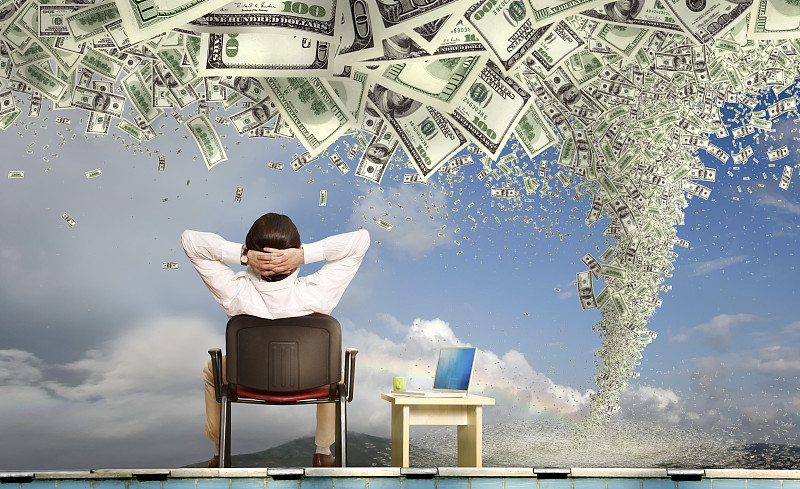 商人用笔记本电脑看着眼前的金钱风暴和龙卷风图片下载